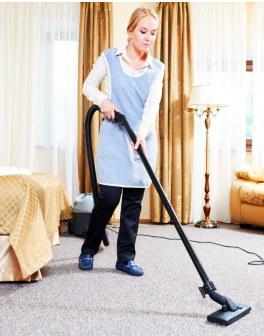 female housekeeping maid worker with vacuum cleaner in room