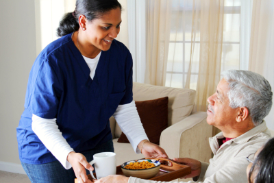 caregiver preparing meal to elderly man