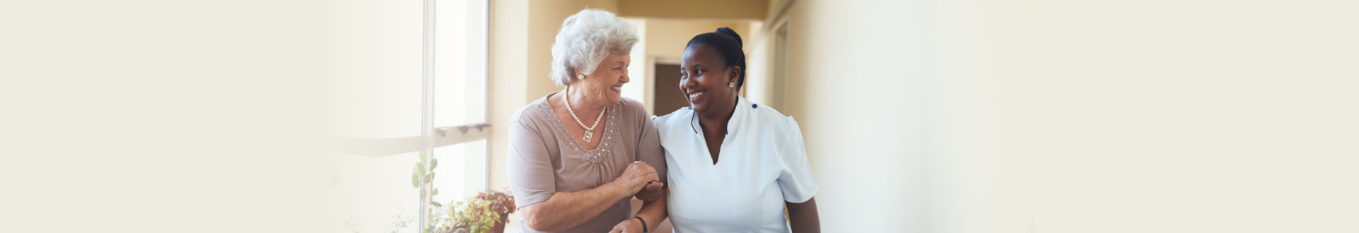 an elderly woman with her caregiver smiling together
